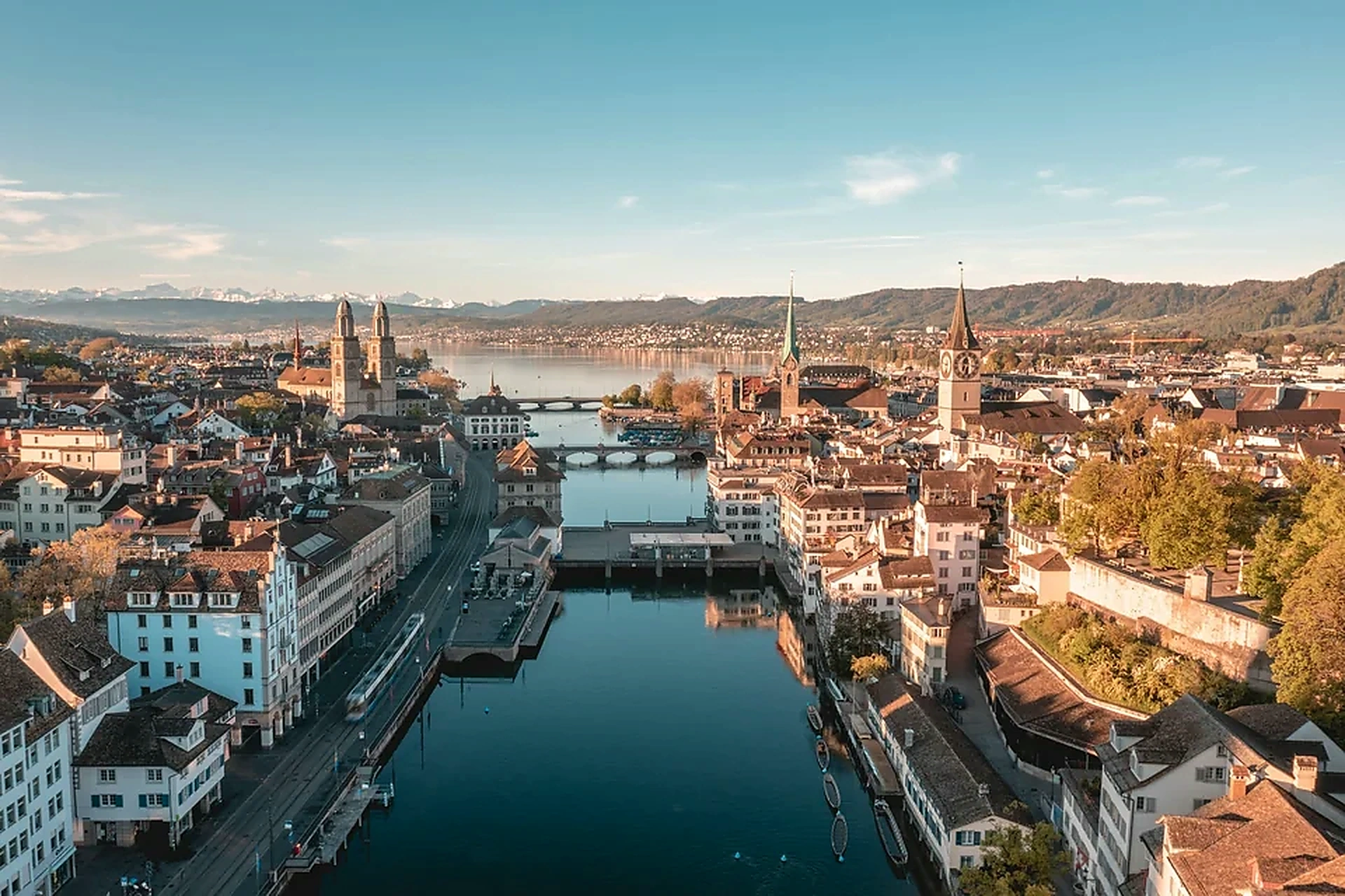 Luftaufnahme der Zürcher Altstadt mit Limmat, Zürichsee und Alpen im Hintergrund.